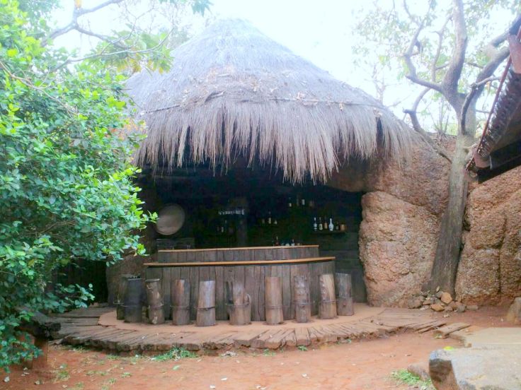 The coolest bar - i am so digging the wood stump stools and thatched roof